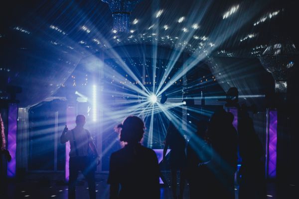 DJ auf einer Hochzeit im Westerwald, Menschen feiern fröhlich, während eine Discokugel von weißen Lichtern angestrahlt wird.