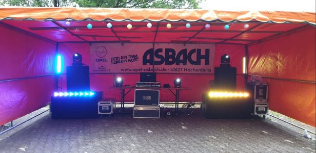 Orangefarbenes Zelt mit aufgebauter PA-Anlage, Moving Heads und LED-Bars.