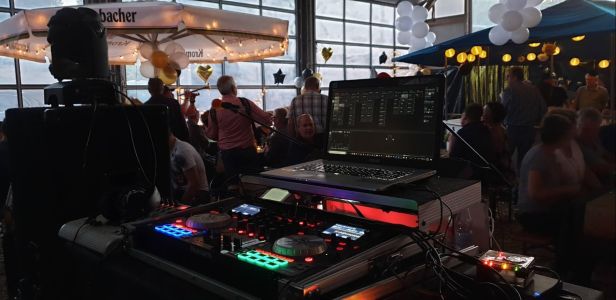 Aus der Perspektive des DJs: Hoffest in Liebenscheid mit sichtbarem Laptop, DJ-Pult und Live-Band auf der Bühne.